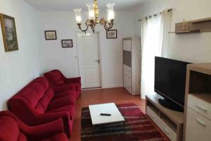 uma sala de estar com cadeiras vermelhas e uma televisão de ecrã plano em Casa da Mina em Ponta Delgada