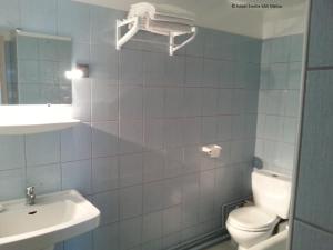 La salle de bains est pourvue de toilettes blanches et d'un lavabo. dans l'établissement Hôtel Emilie, à Royan