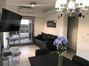a living room with a black couch and a vase of purple flowers at Departamento con Amenities in Pinamar