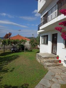 a white house with a balcony and a yard at Dora's House comfortable apartment with a yard and view in Pyrgadikia