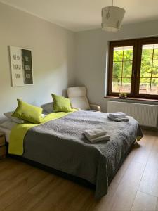 una camera da letto con un letto con cuscini verdi e una sedia di Apartamenty Buczyna w Sierakowie a Sieraków