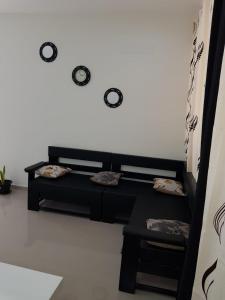 a black couch in a room with clocks on the wall at Bellamy in Porto Novo