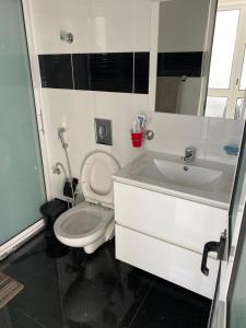 a bathroom with a white toilet and a sink at Bellamy in Porto Novo