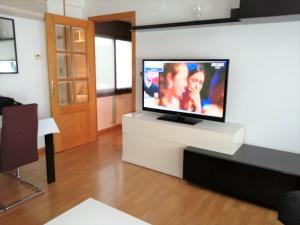 a living room with a flat screen tv on a white stand at APARTAMENTO HUESCA in Huesca