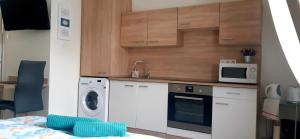 a kitchen with a washing machine and a microwave at Mona apartman in Keszthely