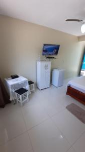a white room with a bed and a tv on the wall at Seasun Suítes in Arraial do Cabo