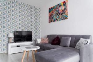 a living room with a gray couch and a tv at APARTAMENT KAMILA in Gdańsk