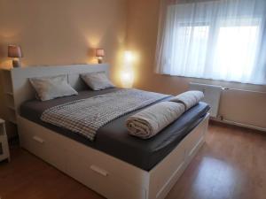 a large bed in a bedroom with two windows at Kölcsey Apartman in Szekszárd