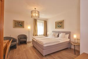 
a bedroom with a bed, a chair, and a lamp at Lodner Hotel Drei Mohren in Lauingen
