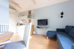 a living room with a blue couch and a tv at Bryza Sopot in Sopot