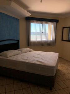 a large bed in a bedroom with a window at Cobertura Frente Mar in Porto Belo