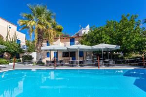 a large swimming pool with chairs and umbrellas at Vanas Apartments in Spetses