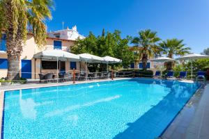a large swimming pool with palm trees and umbrellas at Vanas Apartments in Spetses