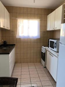 a kitchen with white cabinets and a window and a microwave at Apto Frente Mar in Itapema