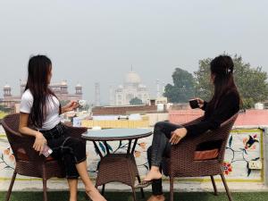 dos mujeres sentadas en una mesa en un techo en Joey's Hostel Agra, en Agra