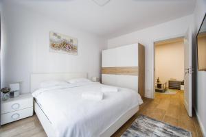 een witte slaapkamer met een wit bed en een raam bij Lovely Home at West Residence in Oradea