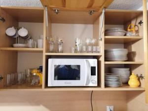 a microwave in a kitchen with plates and dishes at uLitery in Bukowina Tatrzańska