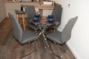 una mesa con cuatro sillas y cuencos azules en ella en TMS Beautiful 2 Bedroom Apartment!Ensuite!Dovestone Lakeside, en West Thurrock