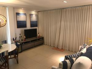 a living room with a couch and a television at Apartamento Iberostate Praia do Forte in Praia do Forte