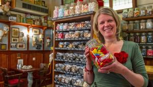 une femme debout dans un magasin tenant une boîte de bonbons dans l'établissement Hotel Hanzestadslogement De Leeuw in het centrum, Snoepwinkel, Hanzemuseum, Koffieschenkerij met Binnenplaats, Kamers met keukentje en Ontbijtservice, à Deventer