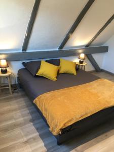 uma cama num quarto com duas almofadas amarelas em Le coin américain em Horbourg