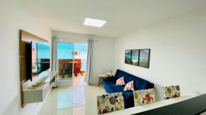 uma sala de estar com um sofá azul e uma televisão em Apto Arraial do Cabo - Condomínio Golden Lake em Arraial do Cabo