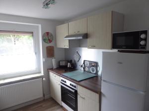 eine Küche mit einem weißen Kühlschrank und einer Mikrowelle in der Unterkunft Ferienwohnung Bochum-Eppendorf in Bochum