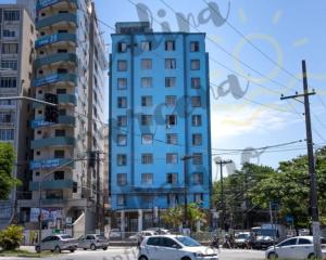 un grand bâtiment bleu dans une rue de la ville avec des voitures dans l'établissement 03 Dormitorios em Frente a Praia do Itararé / S.V, à São Vicente