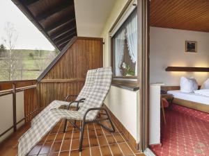 Habitación con balcón con 1 cama y 2 sillas. en Landgasthof Adler Pelzmühle, en Biederbach Baden-Württemberg