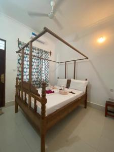 a bedroom with a wooden bed with white sheets at Ndiro Beach House Kendwa in Kendwa