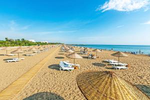 a beach with many chairs and umbrellas and the ocean at Paradise Town Villa Lisa in Belek