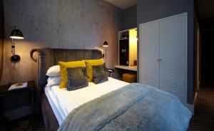 a bedroom with a large bed with yellow pillows at Malmaison London in London