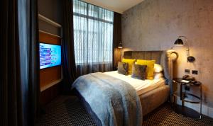 a hotel room with a bed with yellow pillows and a television at Malmaison London in London