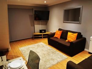 - un salon avec un canapé noir et des oreillers orange dans l'établissement Eagle Drive, à Hendon