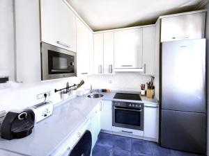 a white kitchen with white cabinets and a refrigerator at Luxury Cercas Bajas Vitoria in Vitoria-Gasteiz