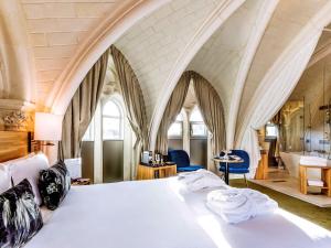 a bedroom with a large white bed with arched ceilings at Mercure Poitiers Centre in Poitiers