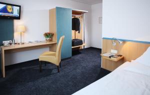 a hotel room with a bed and a desk with a chair at Brackweder Hof in Bielefeld