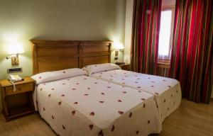 a bedroom with a large bed with a wooden headboard at Hotel Casa Ruba in Biescas