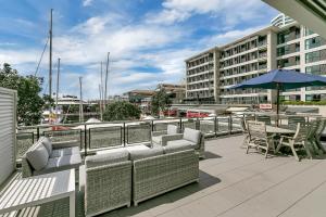 a balcony with couches and tables and an umbrella at Ultimate outdoor-living Urban Getaway! 1 Carpark in Auckland