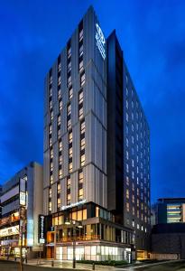 東京的住宿－DEL style Ikebukuro Higashiguchi by Daiwa Roynet Hotel，一座高大的建筑,旁边有一个标志