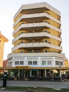 ein hohes gelbes und weißes Gebäude mit Tischen in der Unterkunft Hotel Fabius in Bellaria-Igea Marina