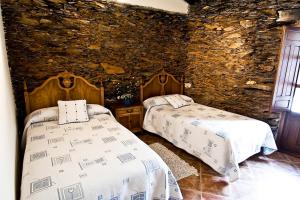 two beds in a room with a stone wall at Casa Rural Aquilamas in La Bastida