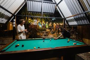 two people playing pool in a greenhouse at Pura Vida Mini Hostel Santa Teresa in Santa Teresa Beach