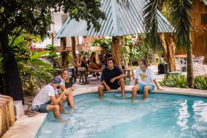 un groupe de personnes assises autour d'une piscine dans l'établissement Pura Vida Mini Hostel Santa Teresa, à Santa Teresa