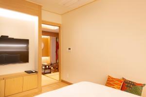1 dormitorio con TV de pantalla plana en la pared en Tomonoya Hotel and Ryokan Gyeongju, en Gyeongju