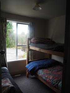 a room with two bunk beds and a window at Berlins cafe, bar and backpackers in Denniston