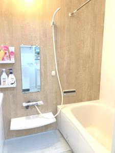La salle de bains est pourvue d'une douche, d'une baignoire et d'un lavabo. dans l'établissement Guesthouse徳島201, à Tokushima
