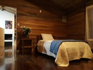 1 dormitorio con 1 cama y pared de madera en Posada Campo Libre, en Baeza