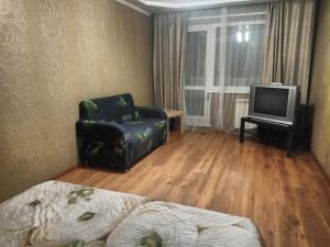 1 dormitorio con silla y TV. en Always at home Apartment OnTransportnaya 11, en Novokuznetsk