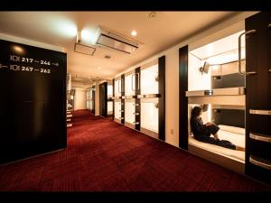 un couloir avec un homme assis à la fenêtre d'un magasin dans l'établissement Capsule Plus Yokohama Sauna & Capsule, à Yokohama